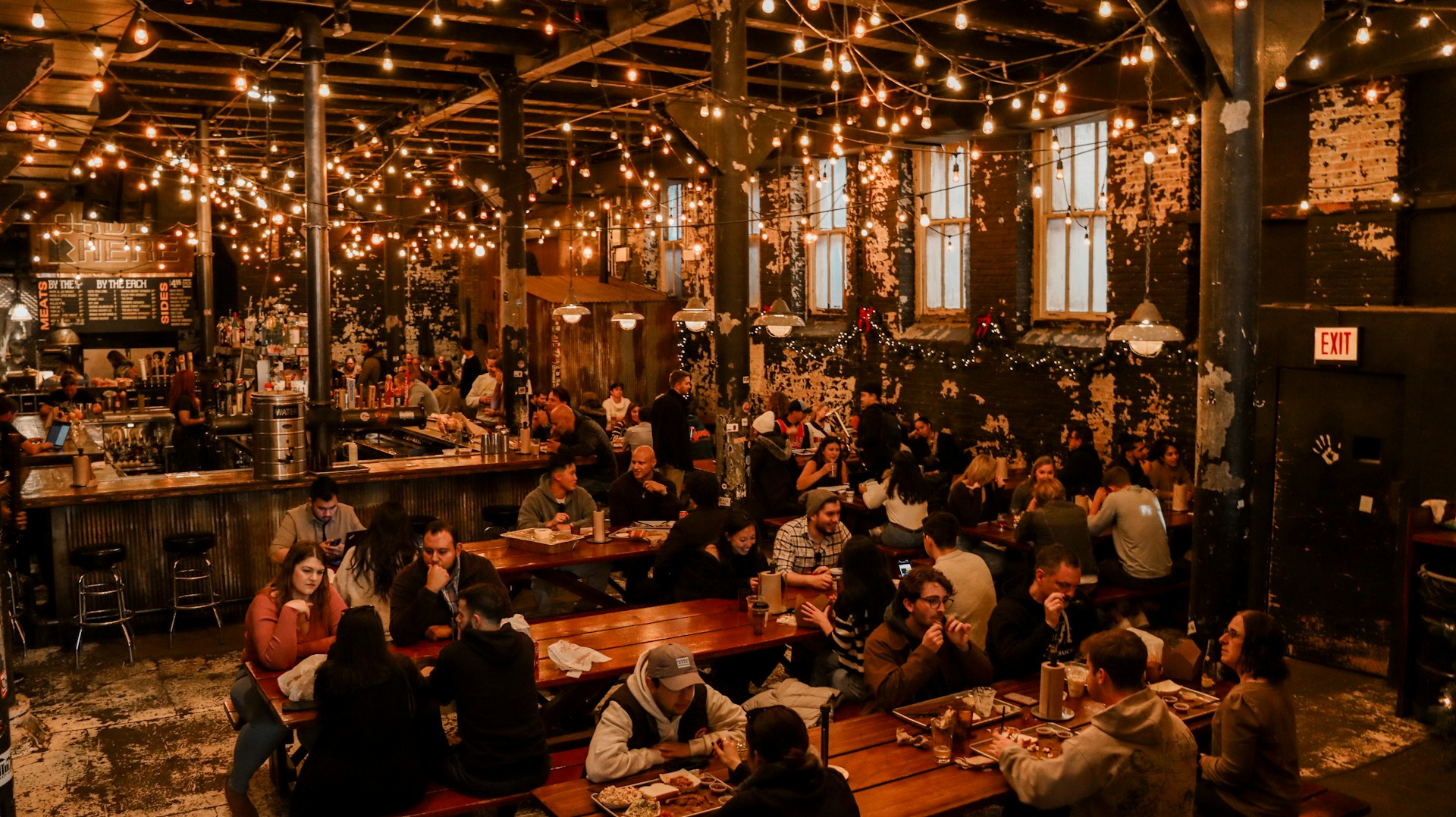 An evening scene inside The Five Pints showing patrons enjoying hearty meals and lively conversation beneath hanging lanterns and Irish flags.