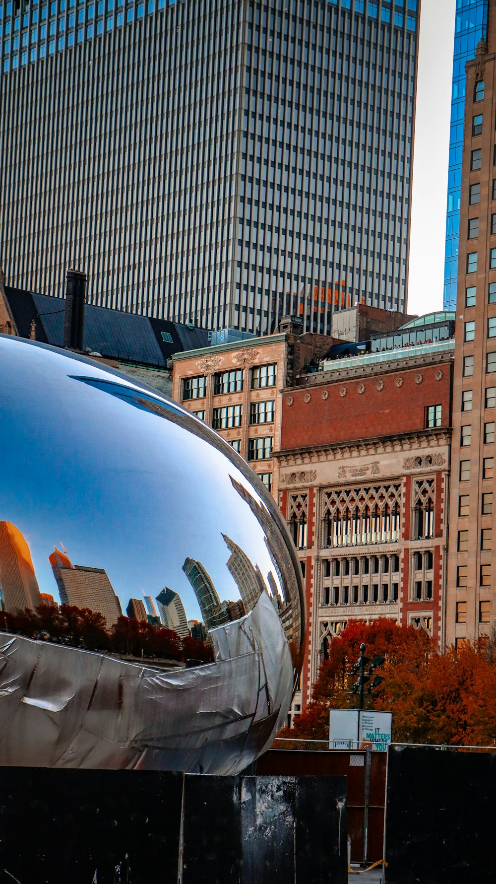 a large shiny metal object sitting in front of a tall building