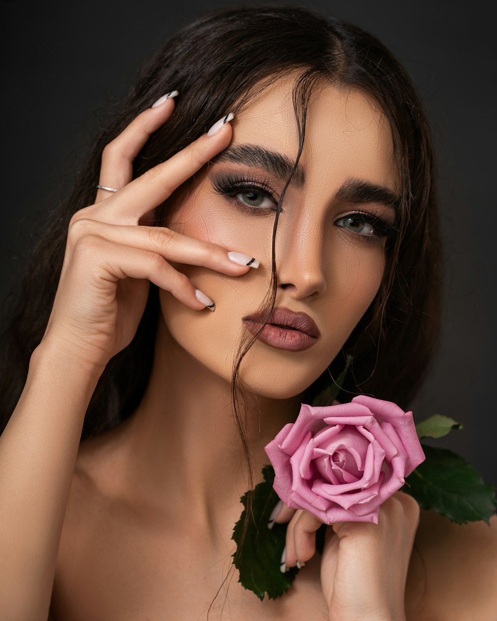 a beautiful woman holding a pink rose in her hand