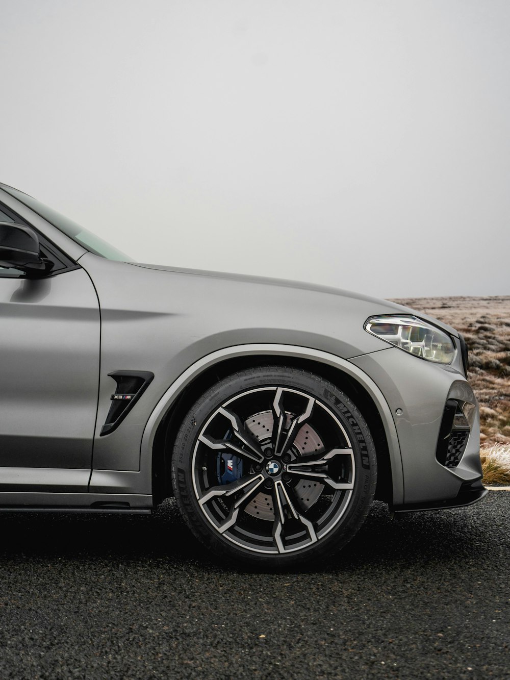 a silver bmw suv parked on the side of the road