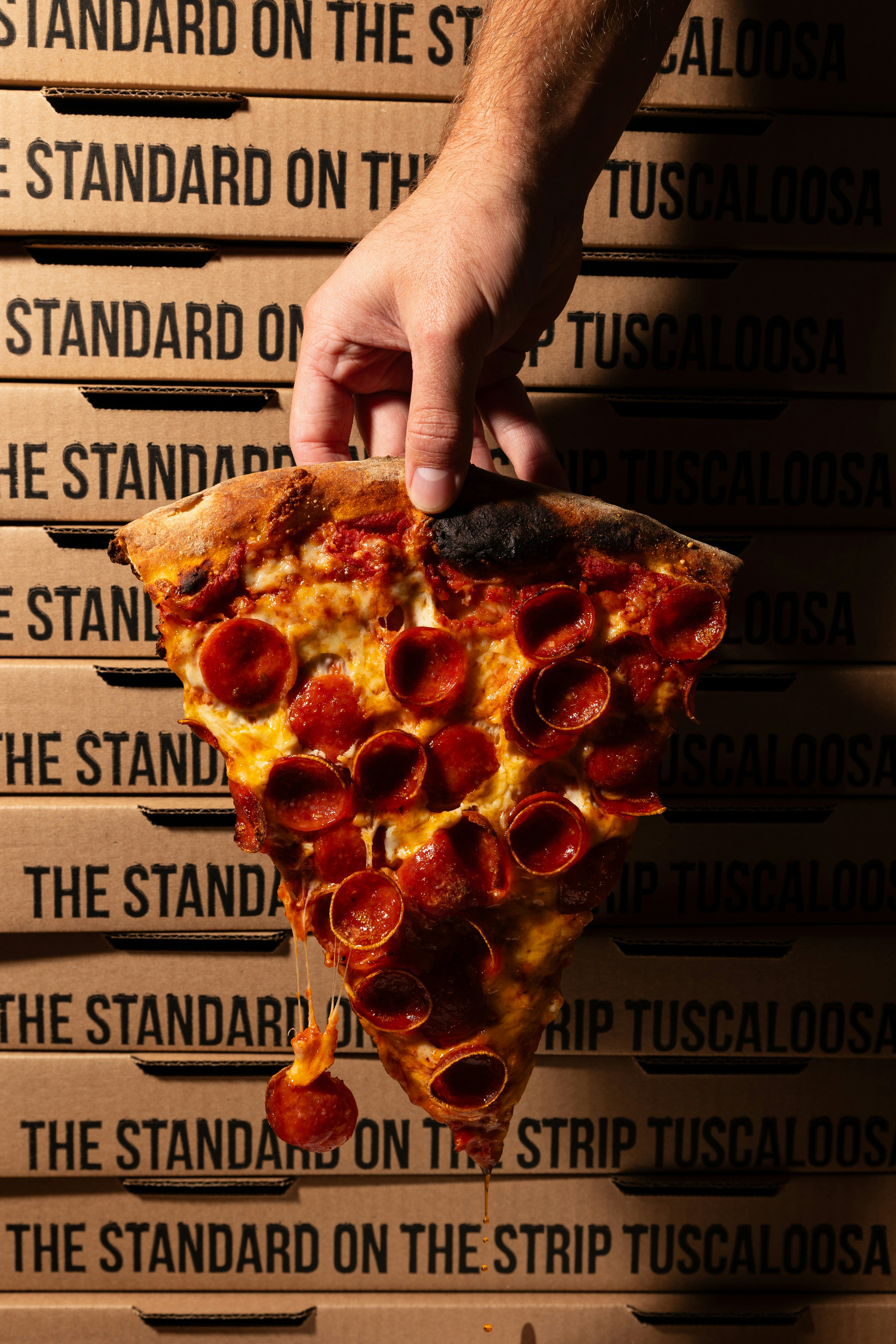 a hand holding a slice of pepperoni pizza