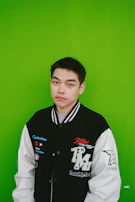 Model wearing a bright green handmade jacket standing against a dark textured wall.