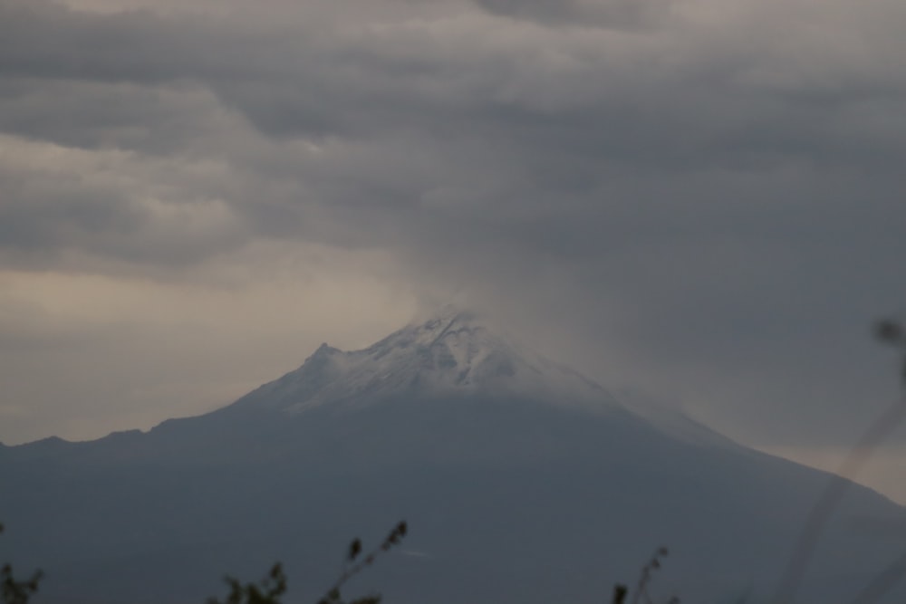 a snow covered mountain in the distance under a cloudy sky