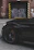 A sleek black car with a shiny gold wrap parked in front of Onyx Auto Collision shop.
