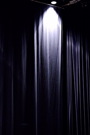 Close-up of a fireproof technical textile curtain being carefully installed in a theater setting.