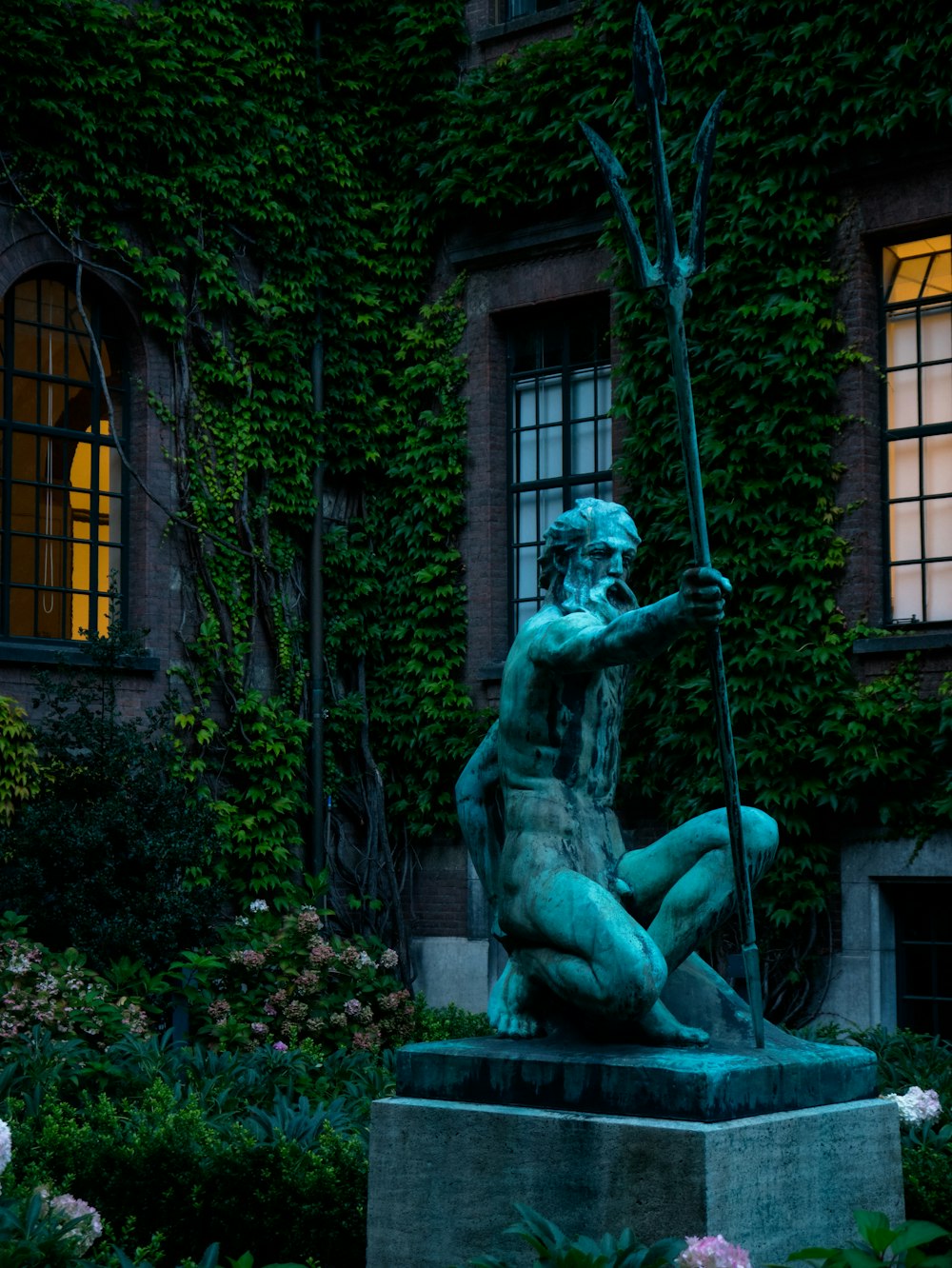 a statue of a man holding a spear in front of a building