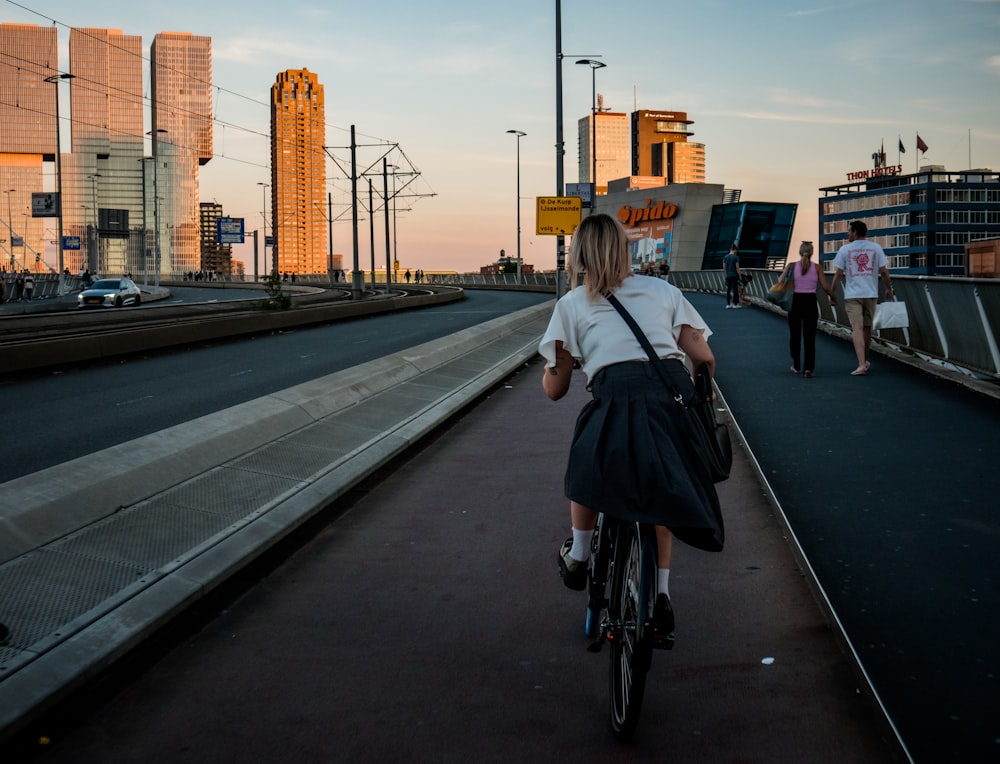 Une femme faisant du vélo dans une rue à côté de grands immeubles