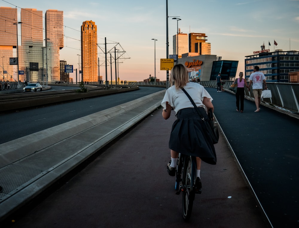 eine Frau, die mit dem Fahrrad eine Straße neben hohen Gebäuden entlangfährt