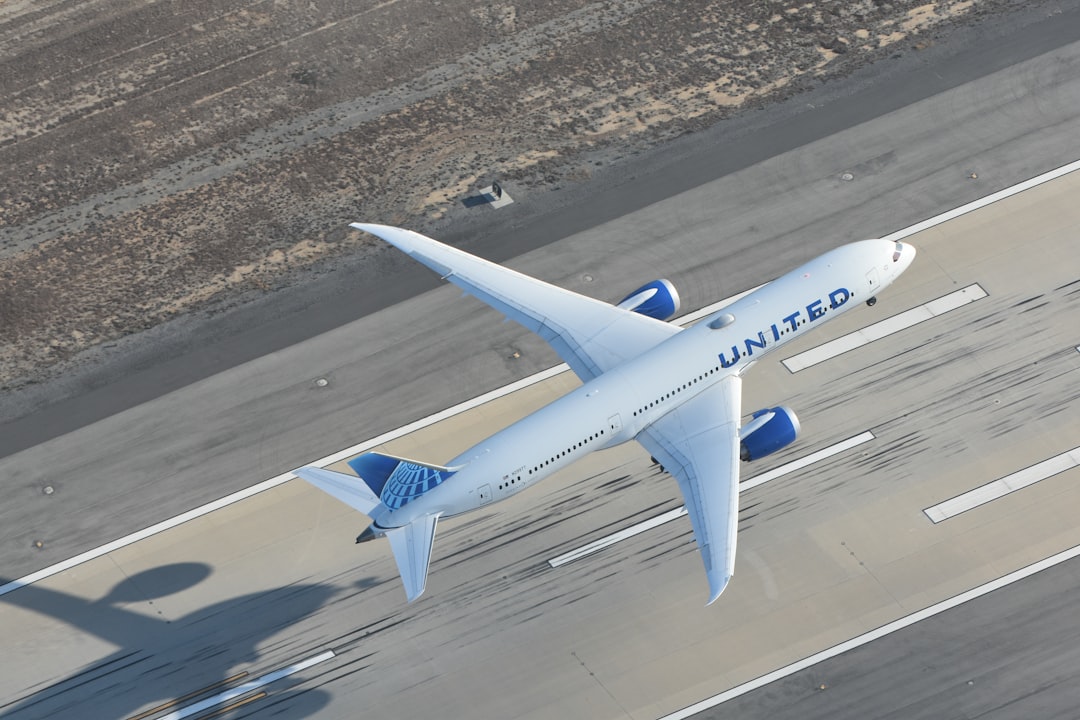 a large jetliner flying over a runway at an airport, United Airlines 787-9 taking off for London