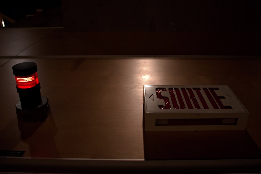 a red light sitting on top of a table next to a sign