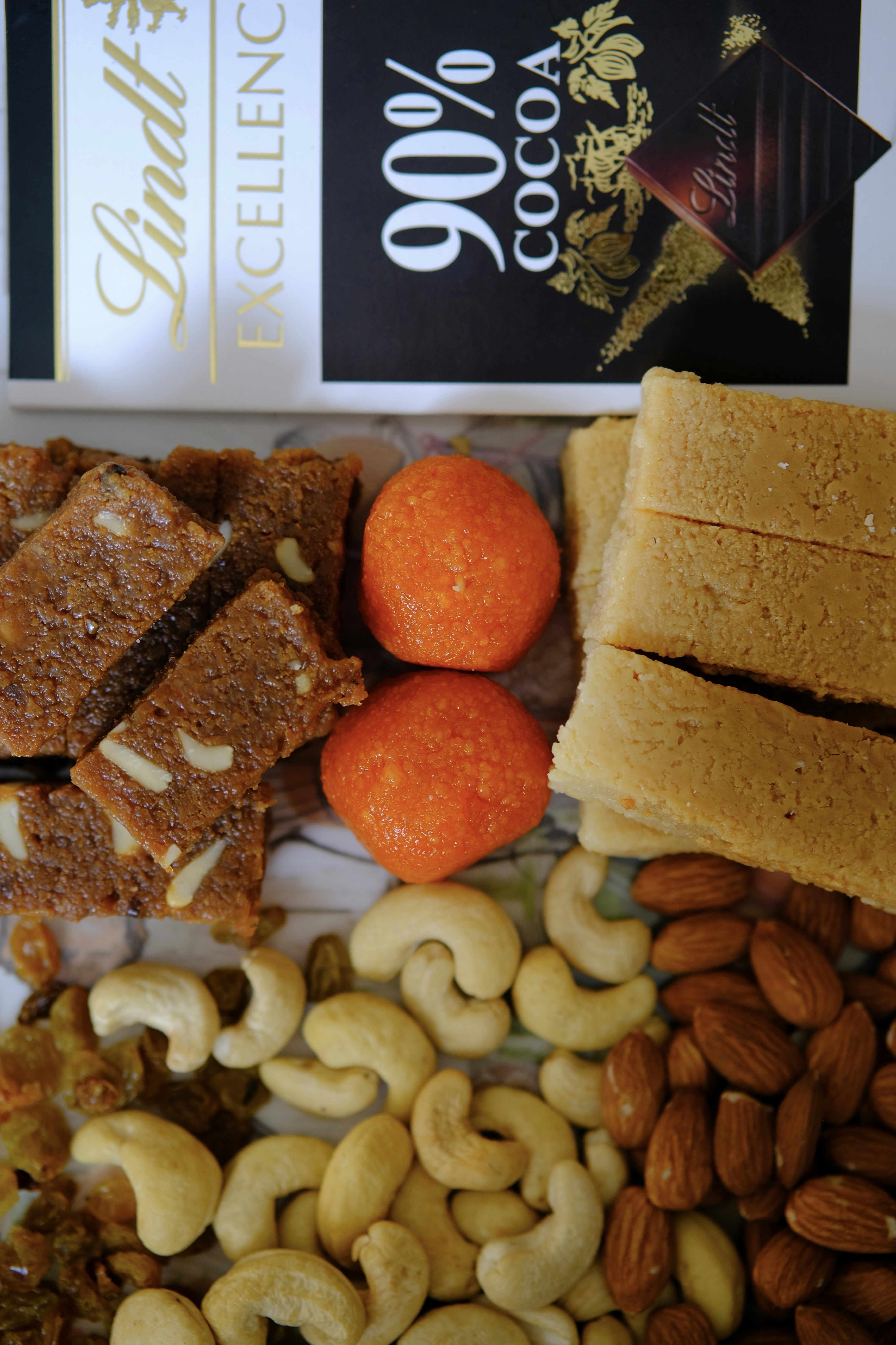 Traditional Indian sweets and specialty mix ingredients on a wooden surface