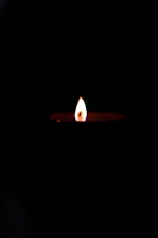 A gentle candle flame glowing softly against a dark background symbolizing remembrance.