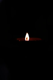A candle flame glowing softly against a dark background, symbolizing memory and hope.