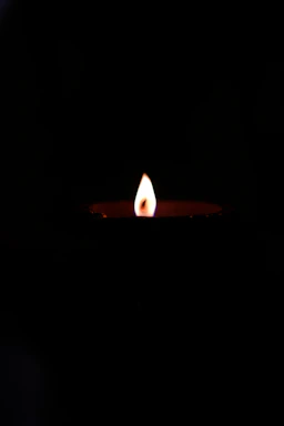 A gentle candle flame glowing softly against a dark background symbolizing remembrance.