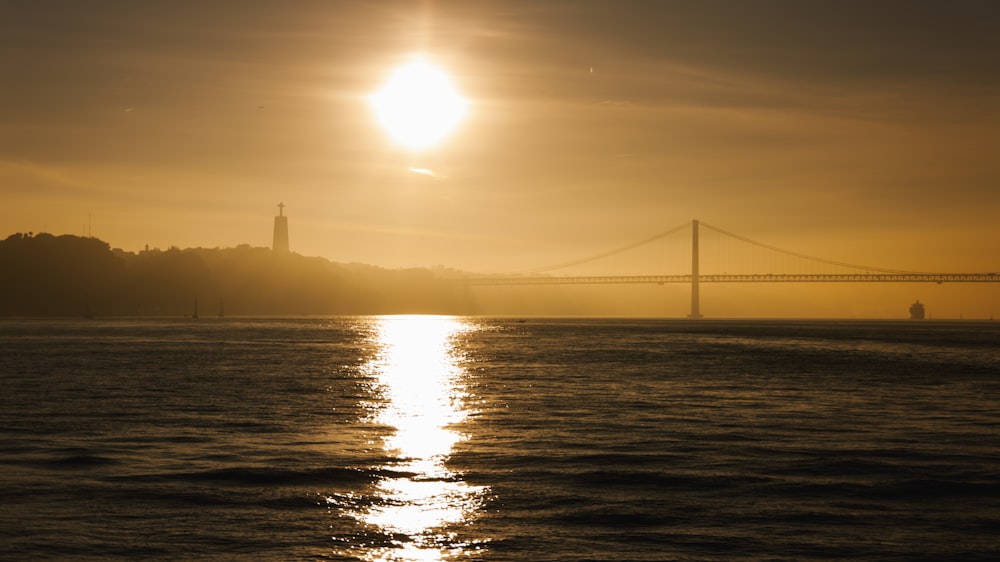 Le soleil se couche sur l’eau avec un pont en arrière-plan