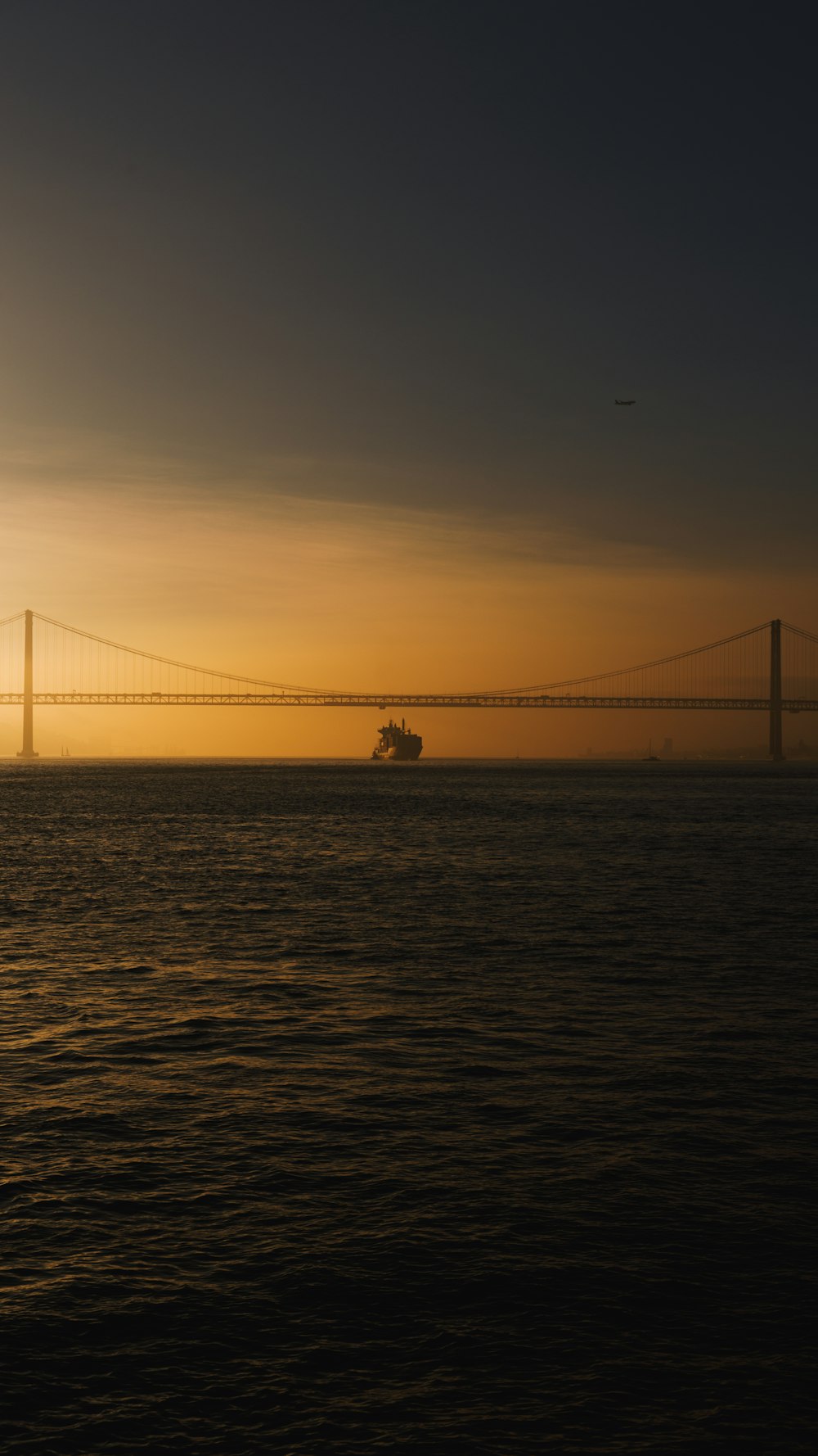 a large ship in the water near a bridge