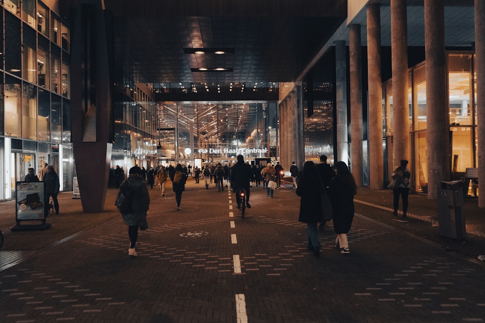 a group of people walking down a street next to tall buildings