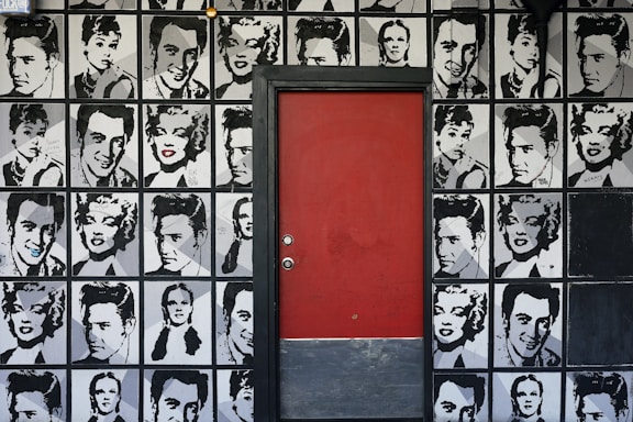 a red door is in front of a wall with black and white pictures of men