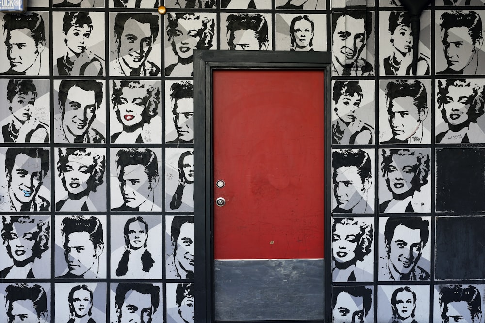 a red door is in front of a wall with black and white pictures of men