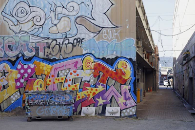 Close-up of a graffiti-covered wall with vibrant colors and layered tags in a narrow Hamburg alley.