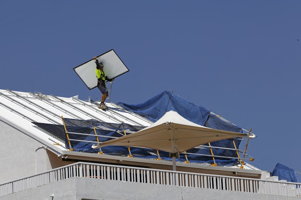 Un homme au sommet d’un toit en train de réparer un panneau solaire