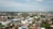 Aerial view of a town with a mixture of residential buildings, commercial structures, and greenery. Mosques and other tall buildings can be seen in various parts of the town. The town is surrounded by a vast landscape that stretches out to the horizon.