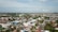 Aerial view of a town with a mixture of residential buildings, commercial structures, and greenery. Mosques and other tall buildings can be seen in various parts of the town. The town is surrounded by a vast landscape that stretches out to the horizon.