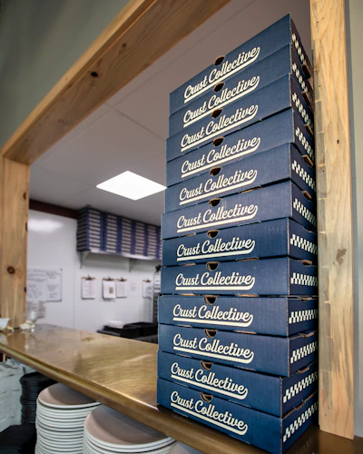 Stack of corrugated pizza boxes in 9-inch, 11-inch, and 12-inch sizes neatly arranged on a wooden table.