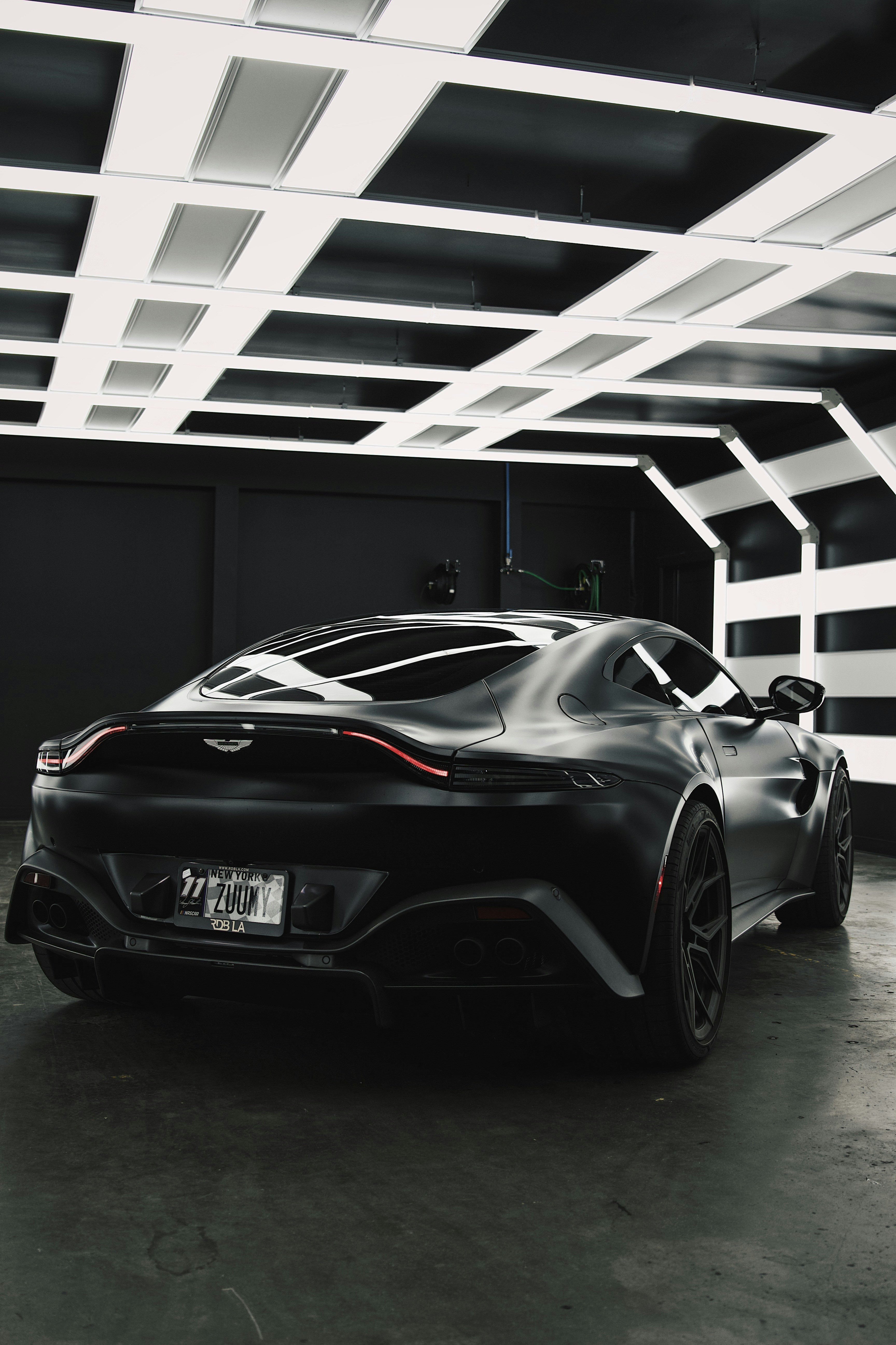 Blue Aston Martin Vantage coupe in dark underground car park, dramatic single spotlight