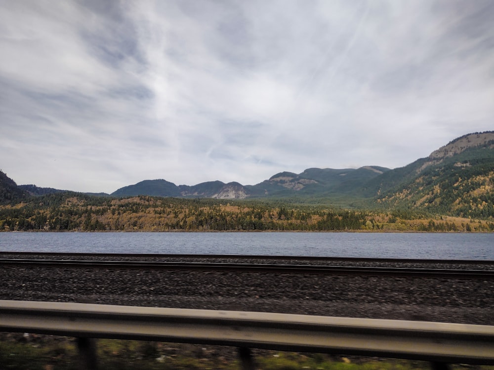 a train traveling past a mountain range next to a lake