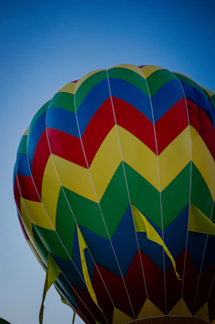 Close-up of a vibrant balloon fabric being inflated on a clear blue sky day