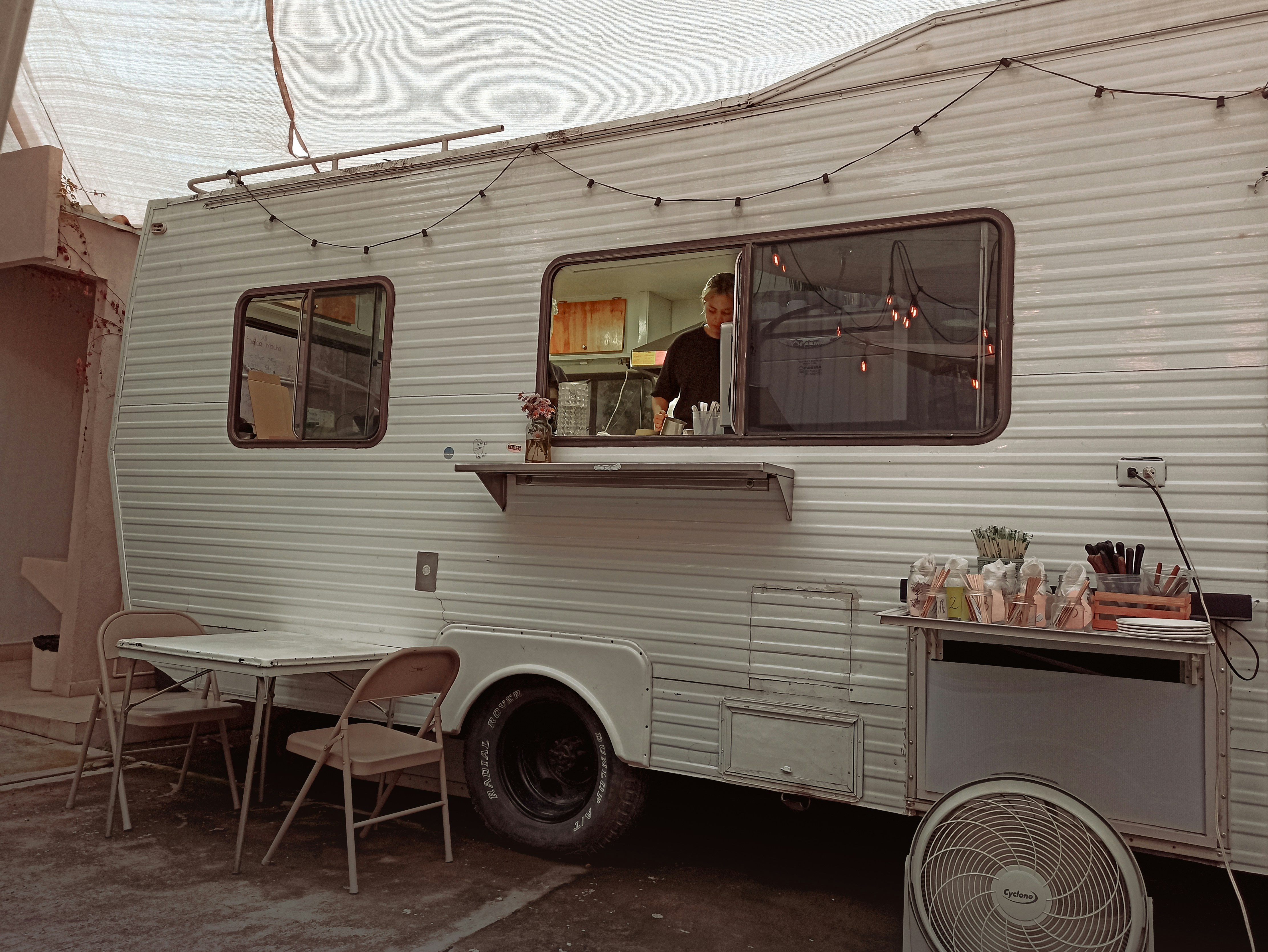 a white trailer parked next to a table and chairs