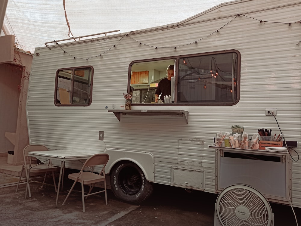 a white trailer parked next to a table and chairs