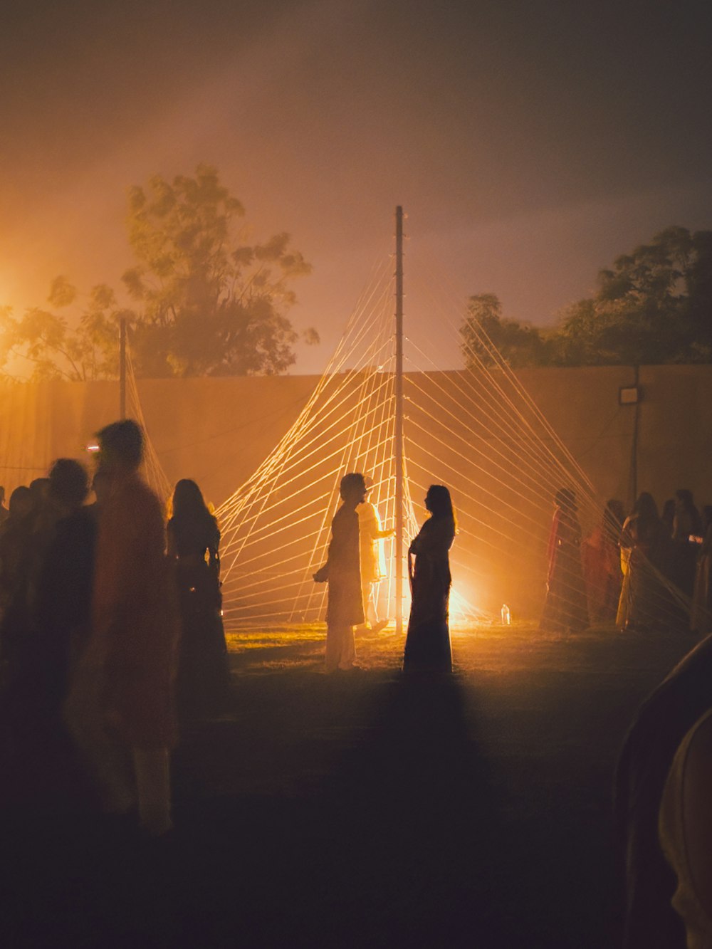 a group of people standing around a tent at night