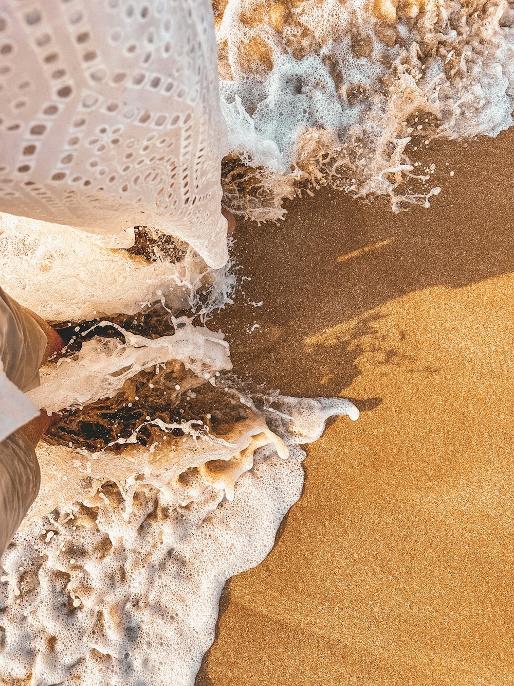 a person standing on a sandy beach next to the ocean