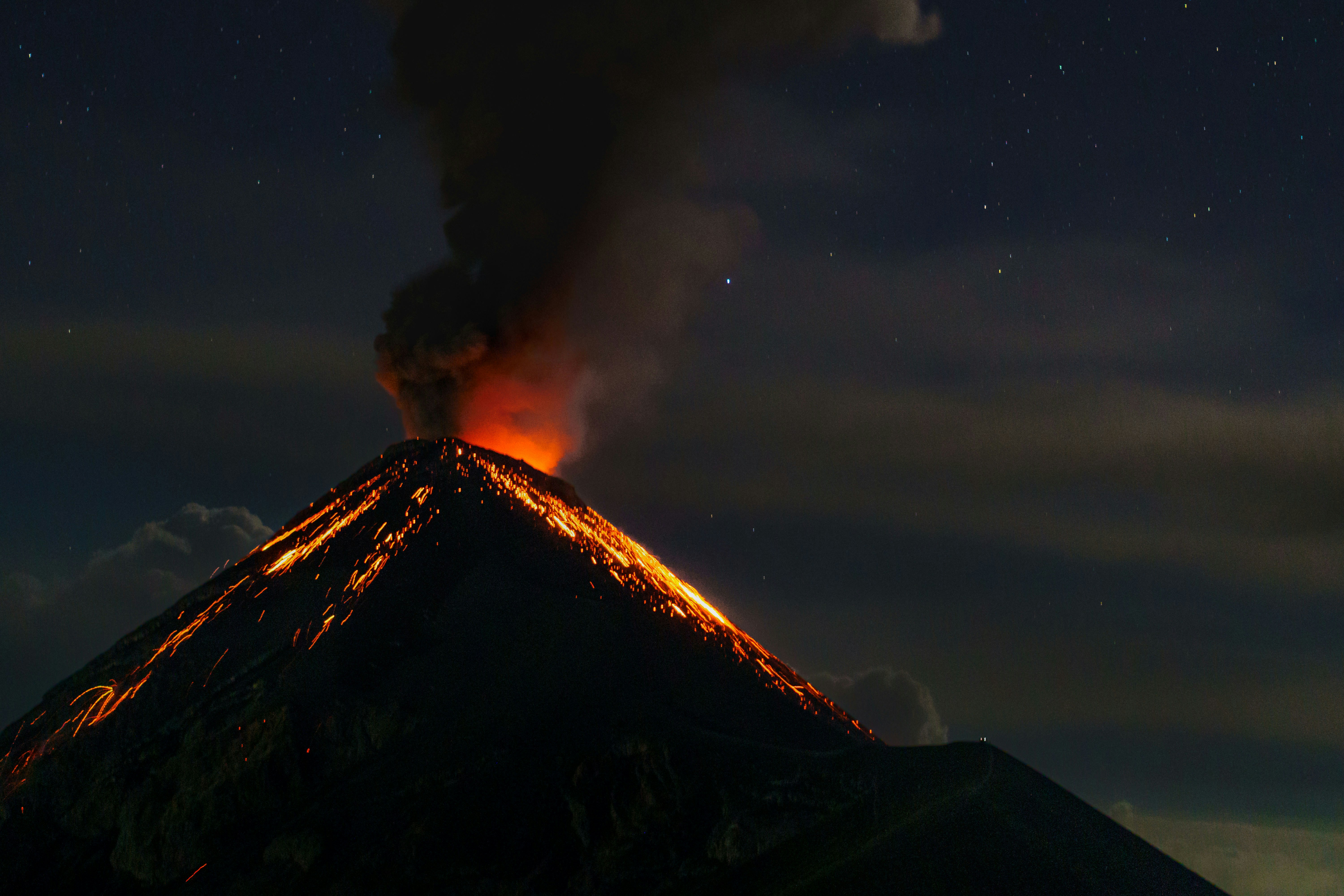 a volcano erupts smoke as it erupts into the night sky, Nature scenery from the Acatenango Volcano, in Alotenango, Guatemala.