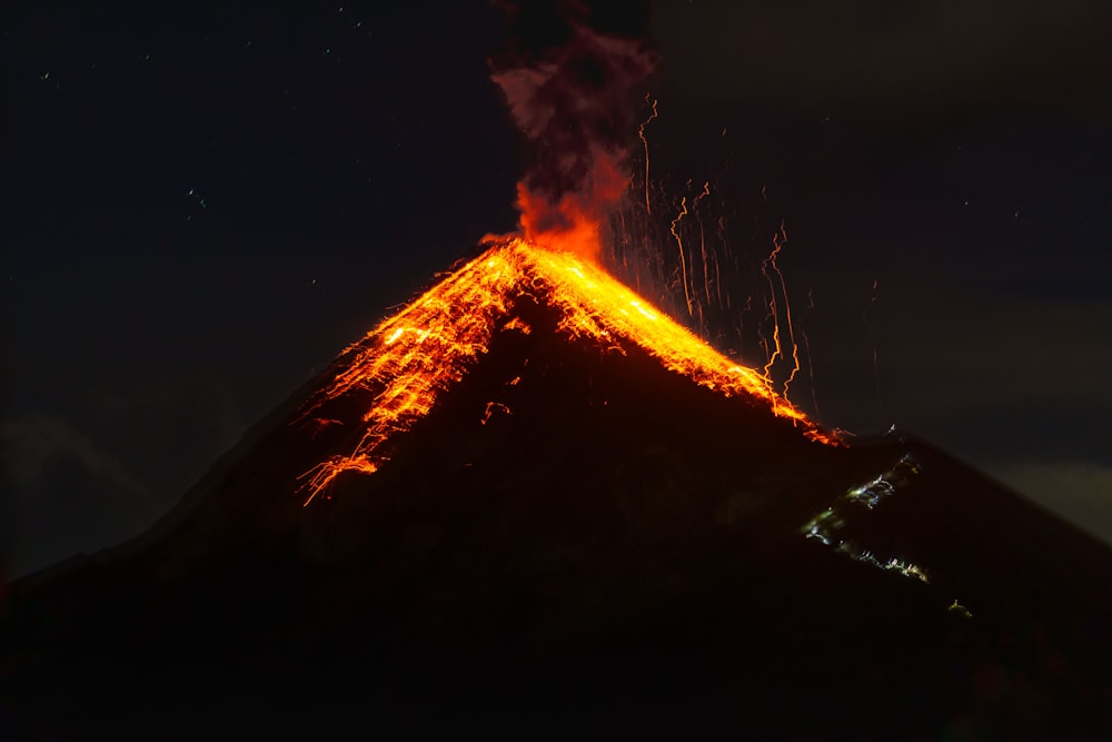 Ein Vulkan lässt Lava ausbrechen, während er in den Nachthimmel ausbricht