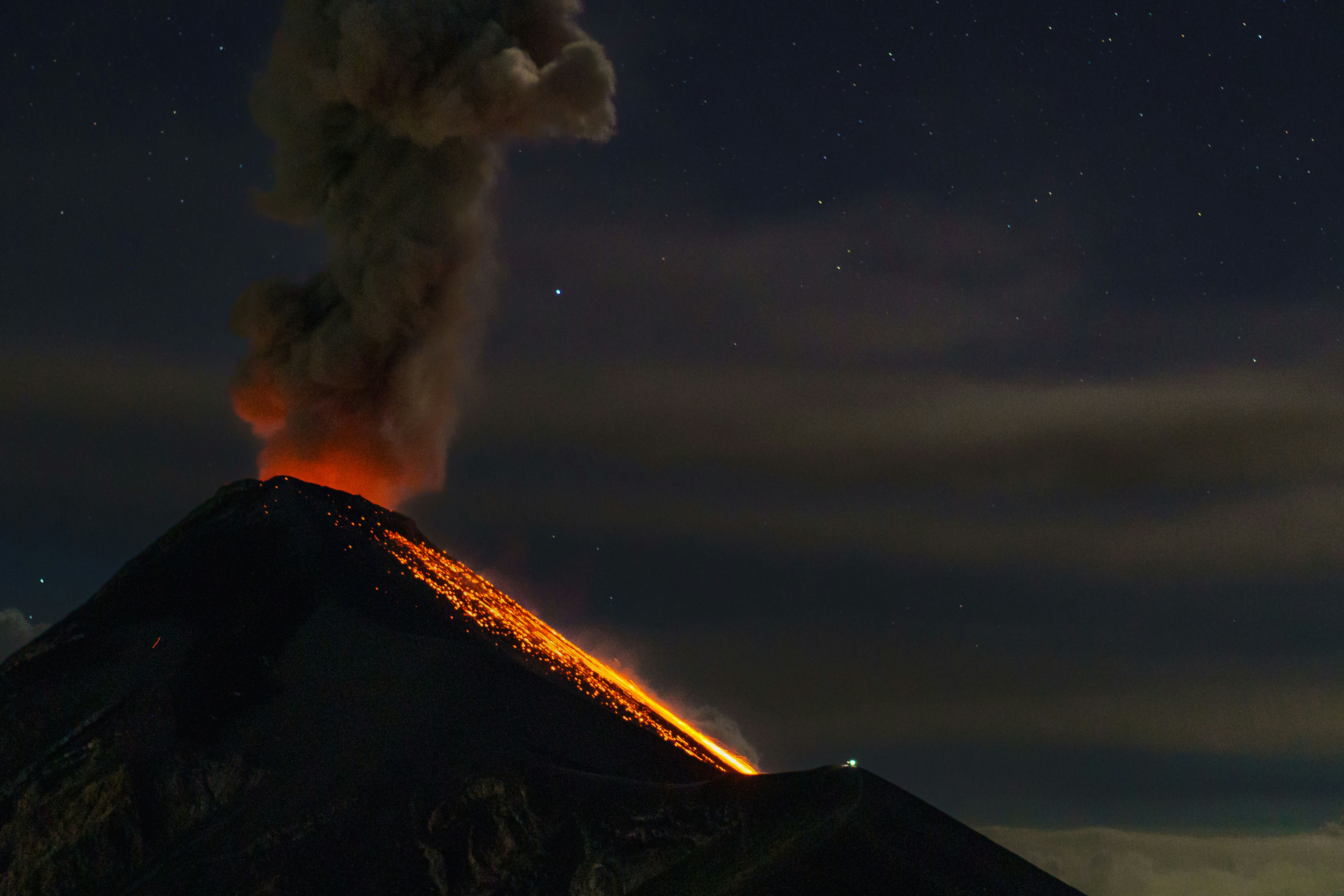 a volcano erupts smoke as it erupts into the night sky, Nature scenery from the Acatenango Volcano, in Alotenango, Guatemala.
