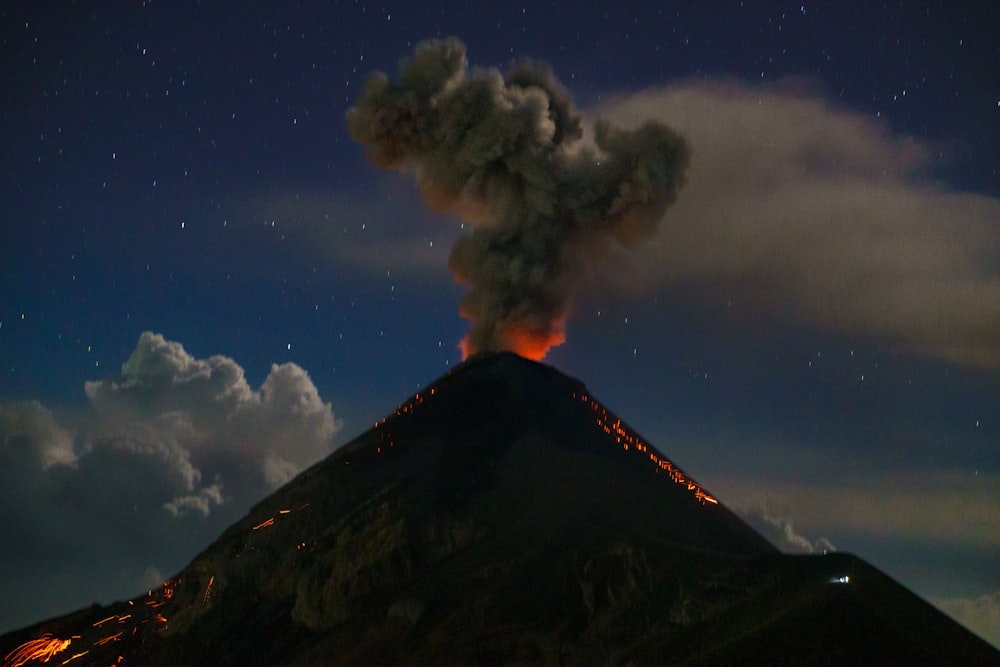 Un vulcano erutta fumo mentre erutta nel cielo notturno