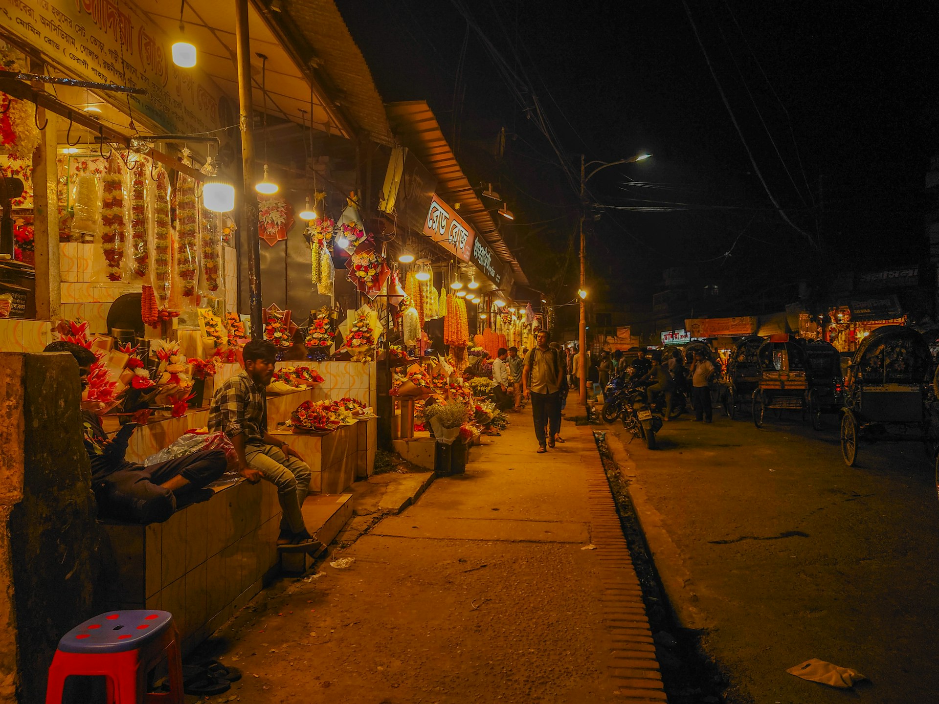 Daily life scene with a man sitting on a bench in front of a local market