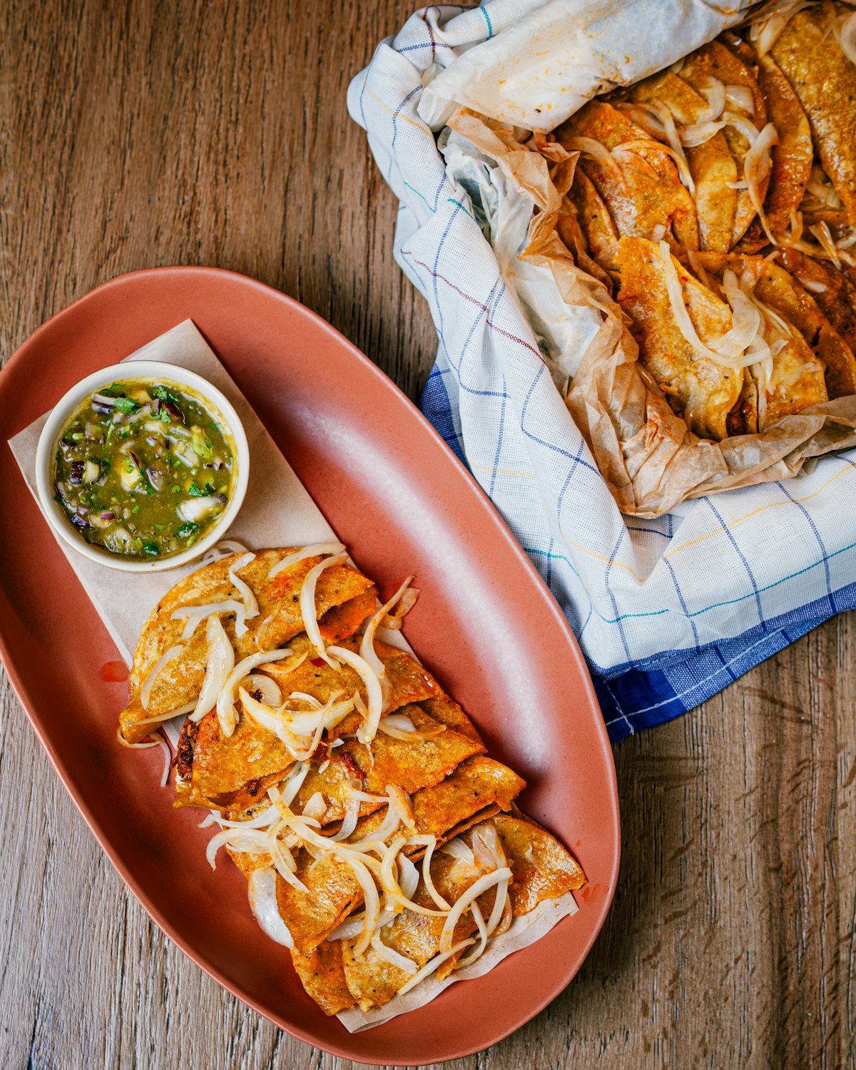 Plate of Mexican enchiladas with red sauce served with rice and beans on wooden table