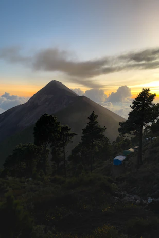 A serene mountain sunrise over the Himalayas with a luxury tent camp in the foreground.