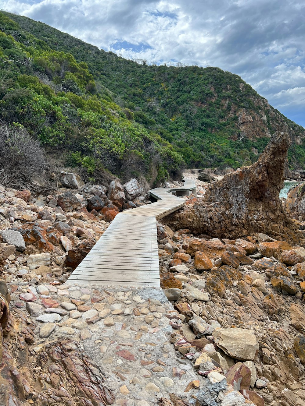 a wooden walkway leading to a rocky beach