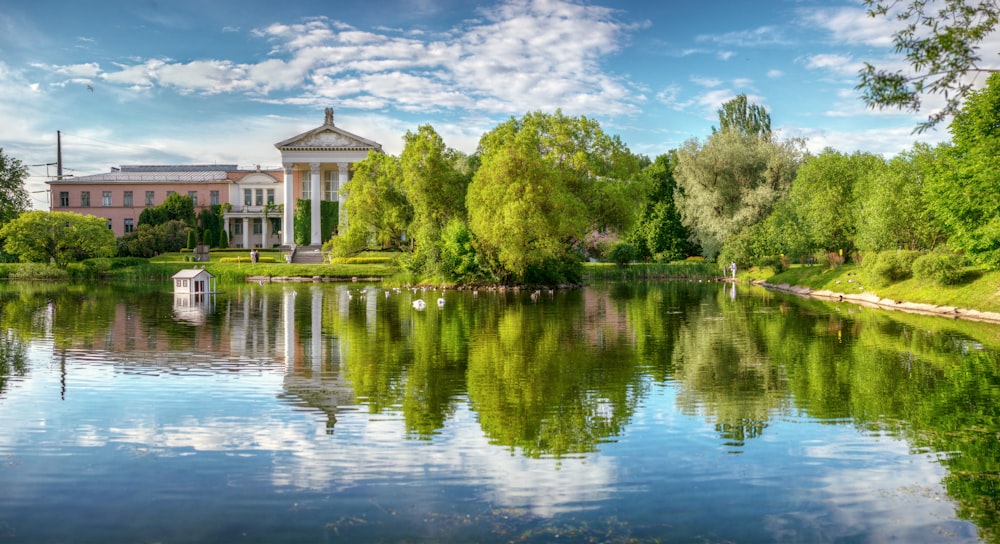 a large building sitting on top of a lush green field next to a lake