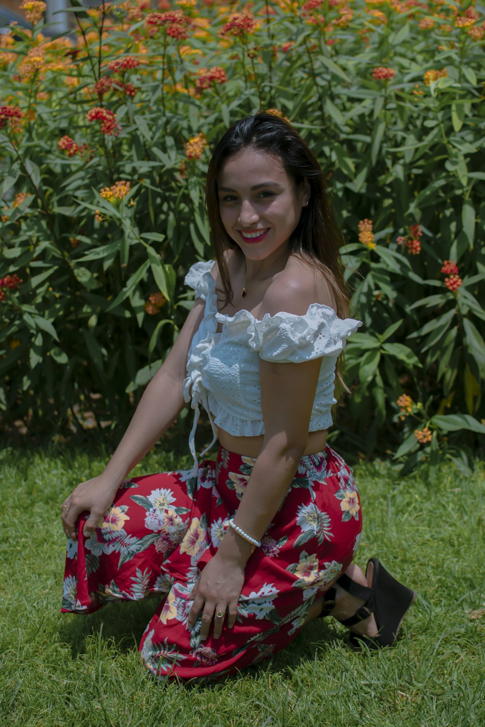 a woman sitting on the grass in front of flowers