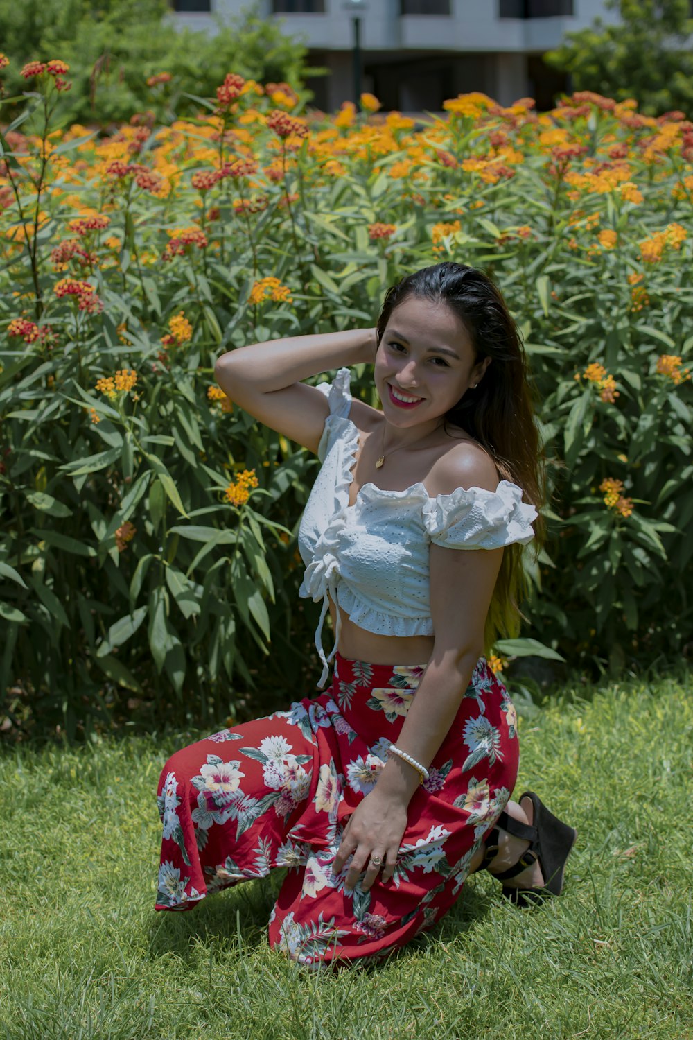 a woman sitting on the ground in front of a field of flowers