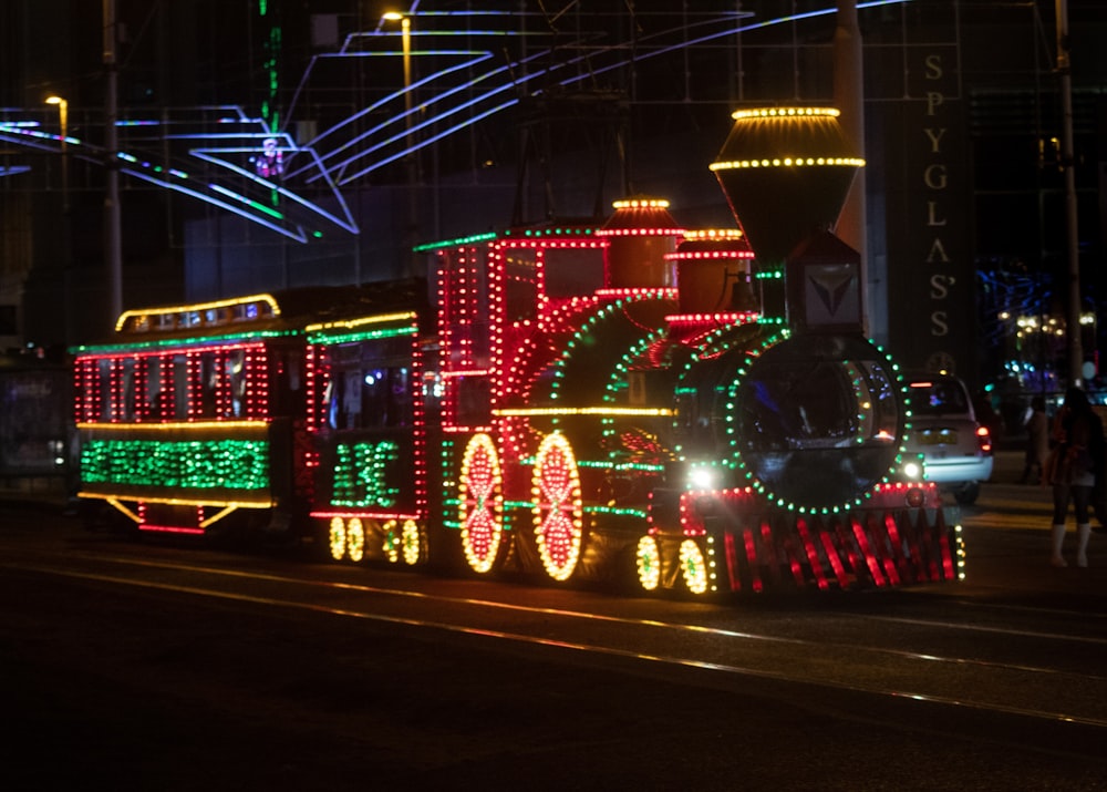 a train decorated with christmas lights on a city street