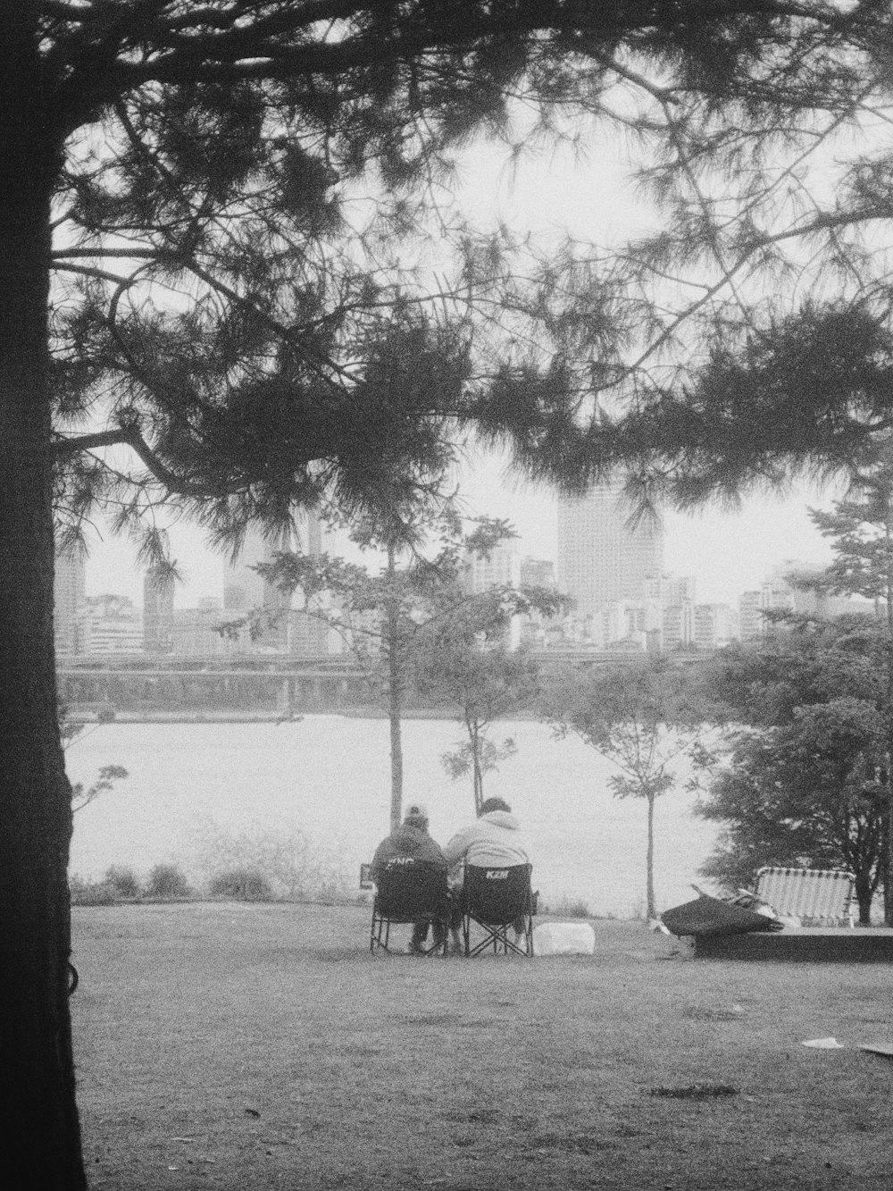 two people sitting on a bench in a park