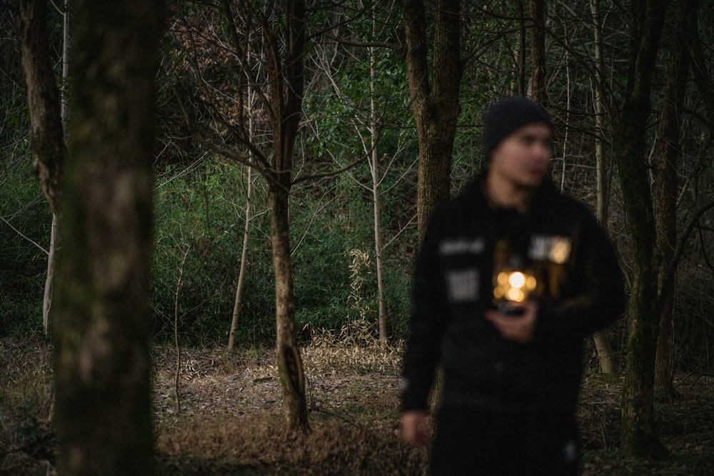 a man standing in the woods holding a flashlight