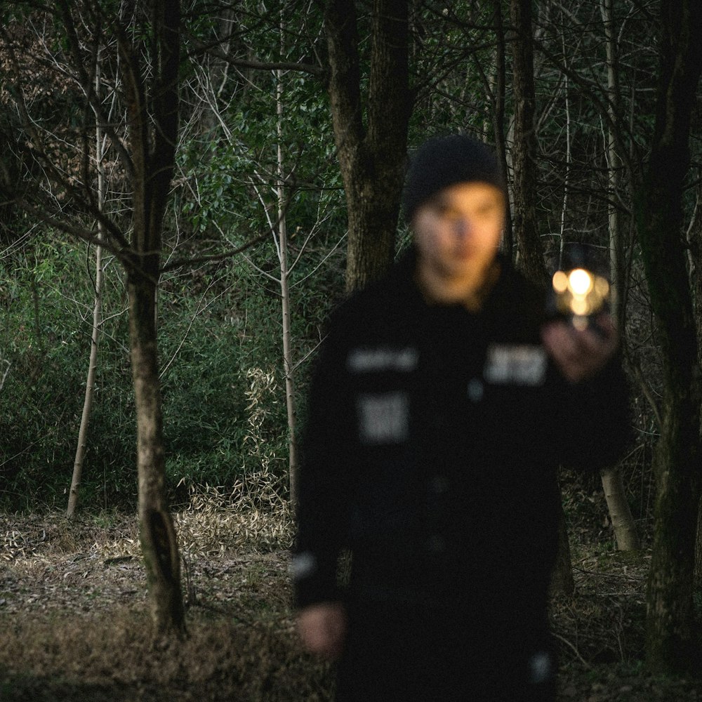 a man standing in the woods holding a flashlight